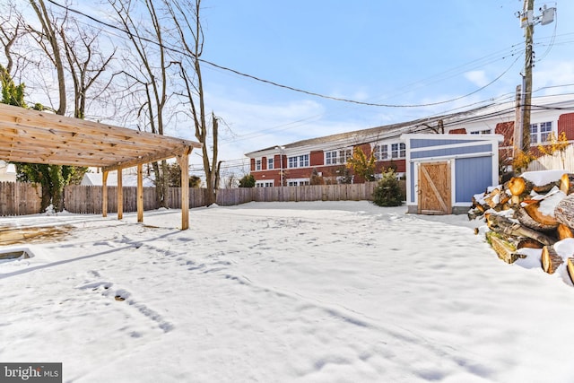 snowy yard featuring a pergola and a shed