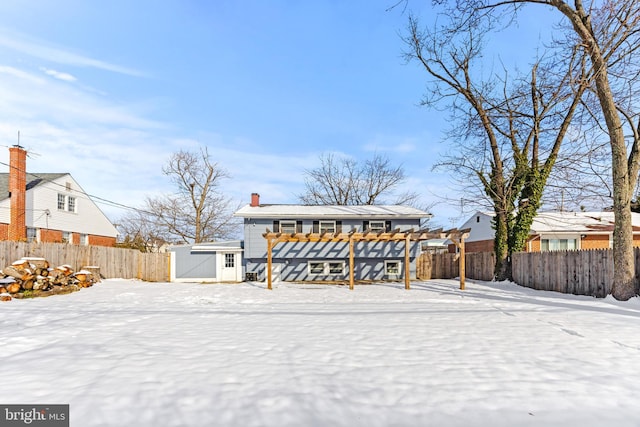 snow covered house featuring a pergola and a shed