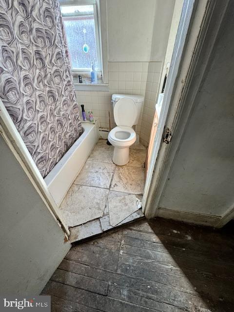 bathroom with shower / tub combo with curtain, tile walls, and toilet