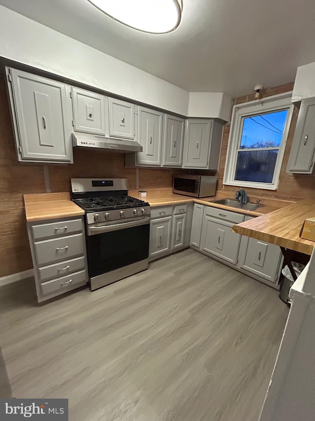 kitchen with appliances with stainless steel finishes, gray cabinets, and exhaust hood