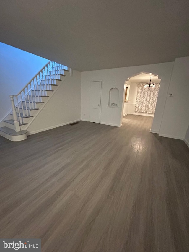 unfurnished living room featuring dark hardwood / wood-style floors and an inviting chandelier