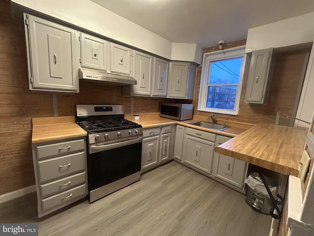 kitchen featuring appliances with stainless steel finishes, gray cabinetry, sink, butcher block counters, and range hood