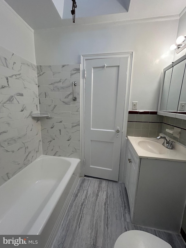 full bathroom featuring toilet, tiled shower / bath, tile walls, vanity, and hardwood / wood-style floors