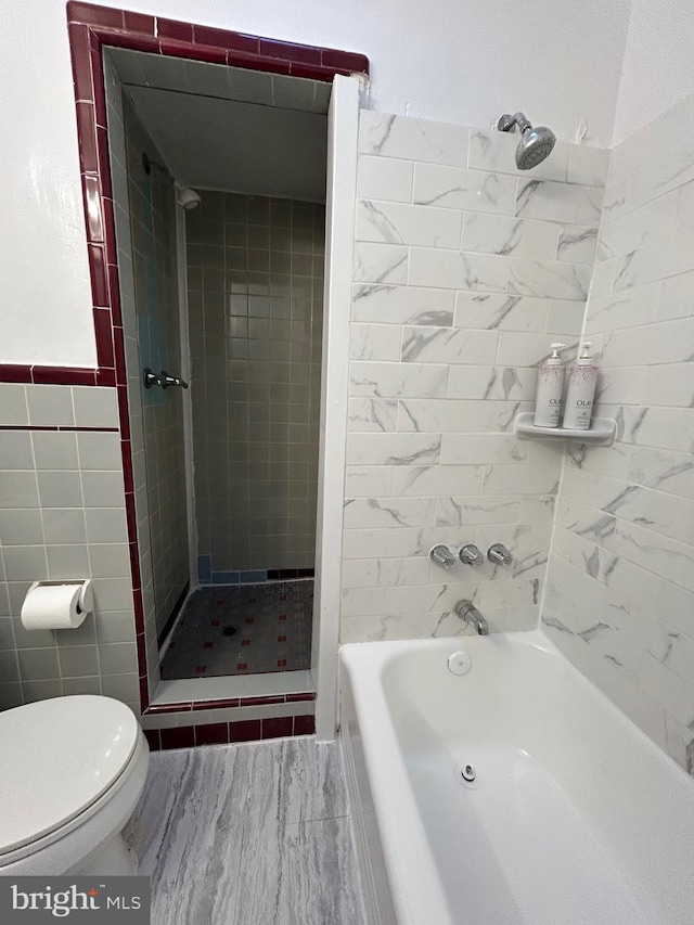 bathroom featuring toilet, tiled shower / bath combo, and tile walls