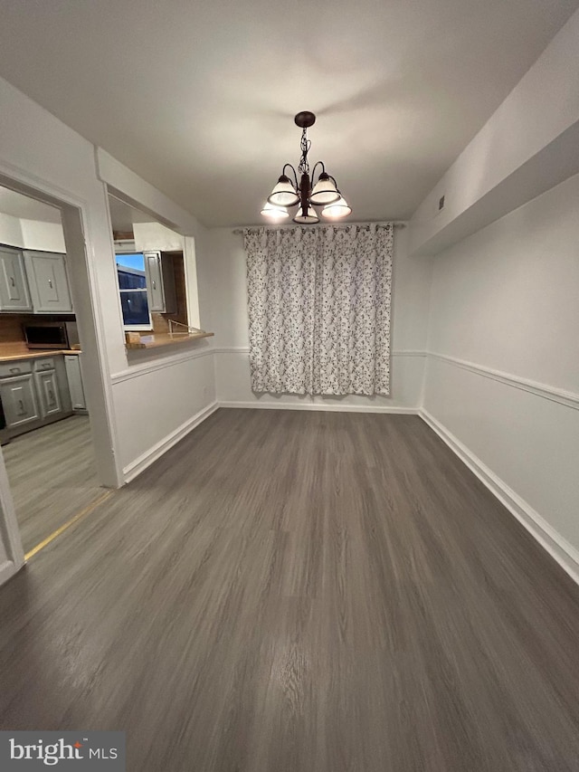 unfurnished dining area featuring dark hardwood / wood-style floors and an inviting chandelier