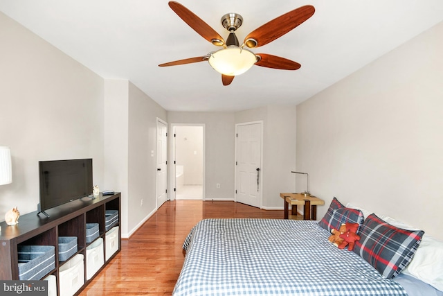 bedroom with light wood-type flooring, ceiling fan, and connected bathroom