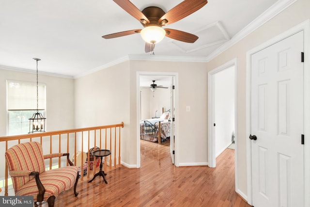 living area with ceiling fan with notable chandelier, light hardwood / wood-style flooring, and crown molding