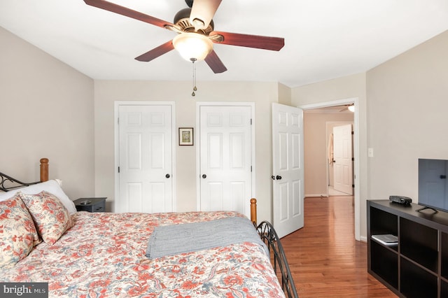 bedroom with two closets, ceiling fan, and light hardwood / wood-style floors