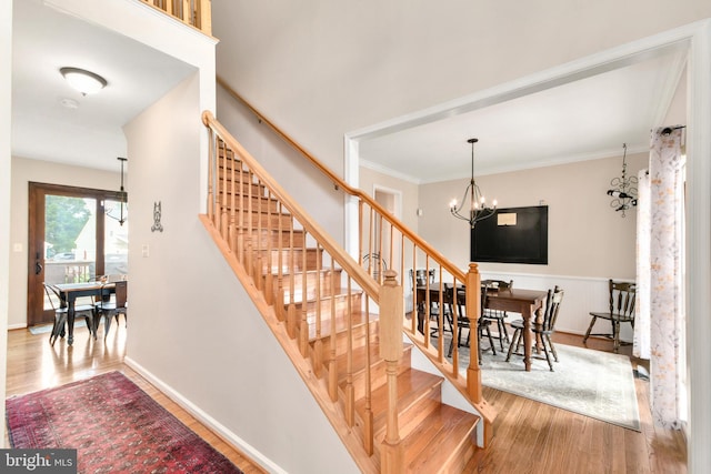 staircase featuring crown molding, hardwood / wood-style floors, and a chandelier