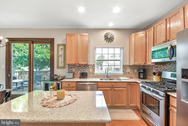 kitchen featuring a wealth of natural light, light stone countertops, sink, and appliances with stainless steel finishes