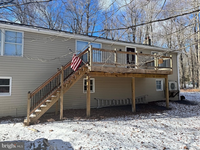 snow covered rear of property with a wooden deck and ac unit