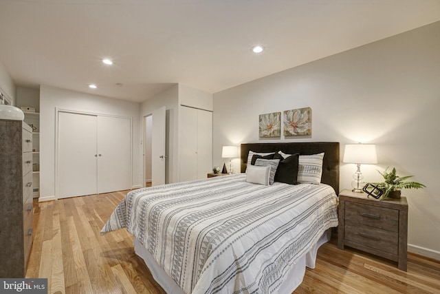 bedroom with multiple closets and light wood-type flooring