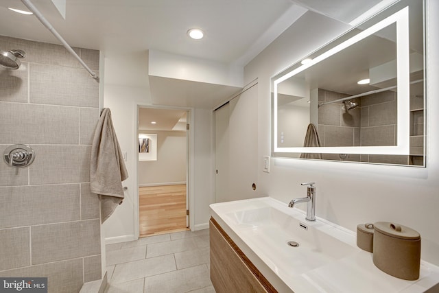 bathroom with tiled shower, vanity, and tile patterned floors