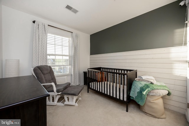 carpeted bedroom featuring wood walls and a crib