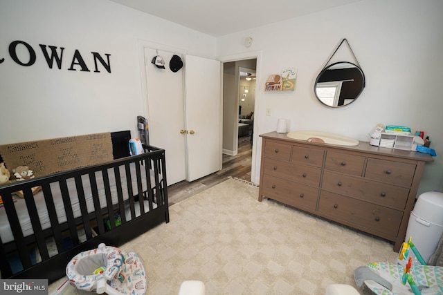 bedroom with light hardwood / wood-style floors and a crib