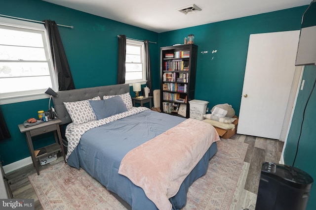 bedroom featuring multiple windows and light hardwood / wood-style flooring