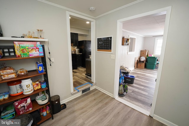 corridor with light hardwood / wood-style floors and ornamental molding