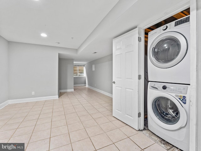 laundry area with light tile patterned floors and stacked washer / dryer