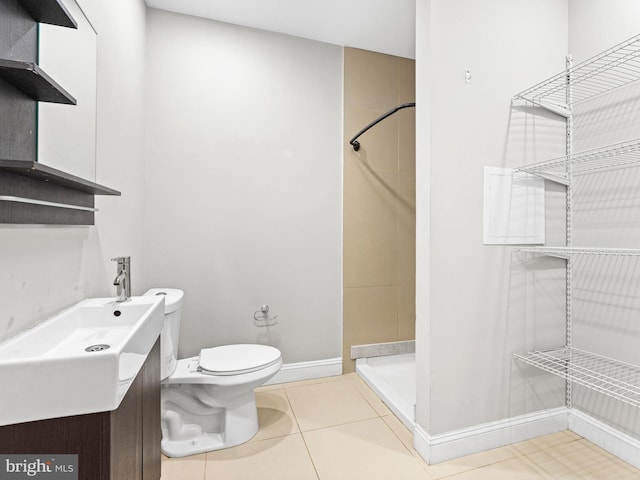 bathroom featuring tile patterned flooring, vanity, toilet, and walk in shower