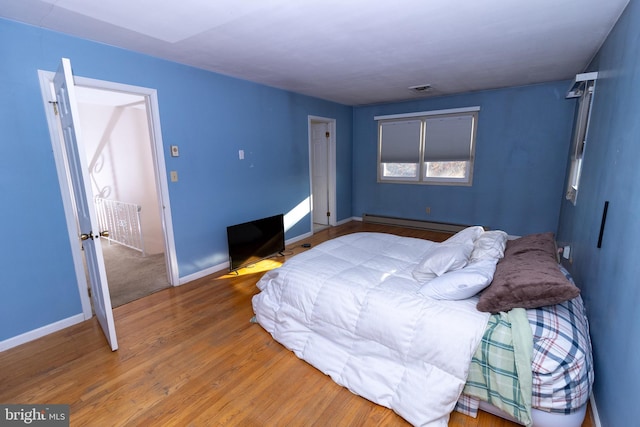 bedroom with hardwood / wood-style flooring and a baseboard heating unit