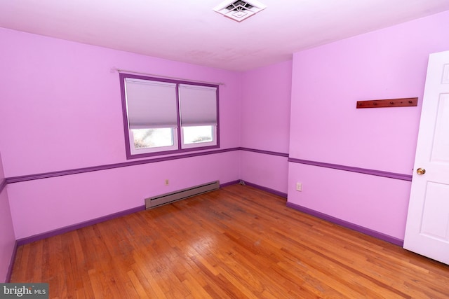 unfurnished room featuring baseboard heating and light wood-type flooring