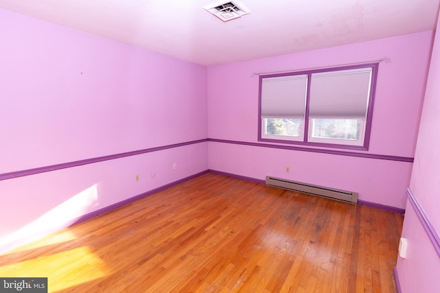 empty room with hardwood / wood-style floors and a baseboard radiator