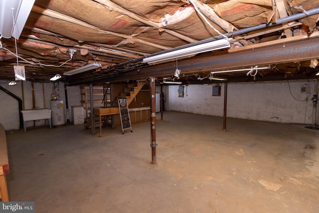 basement featuring electric panel, sink, gas water heater, and water heater