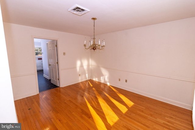 unfurnished room with a chandelier and dark wood-type flooring