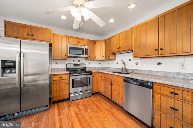 kitchen featuring backsplash, stainless steel appliances, ceiling fan, sink, and light hardwood / wood-style flooring