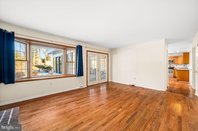 unfurnished living room featuring french doors, light hardwood / wood-style flooring, and sink