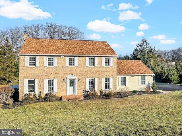 colonial home featuring a front lawn