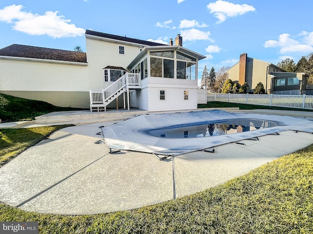 back of house featuring a sunroom, a patio, and a covered pool