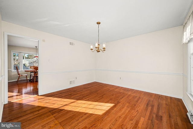 unfurnished room with wood-type flooring and a notable chandelier