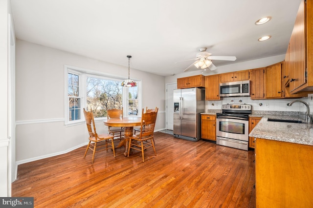 kitchen featuring backsplash, sink, hanging light fixtures, ceiling fan, and stainless steel appliances