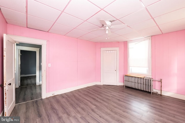 spare room featuring a paneled ceiling, ceiling fan, radiator heating unit, and dark hardwood / wood-style floors