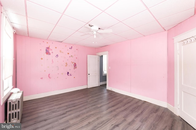 spare room with ceiling fan, radiator heating unit, a drop ceiling, and dark hardwood / wood-style floors