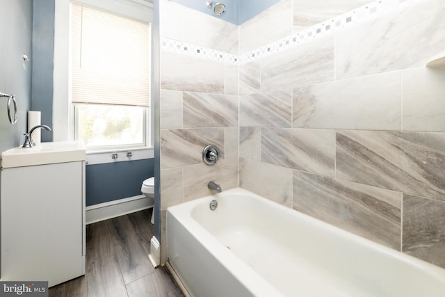 full bathroom featuring hardwood / wood-style floors, vanity, tiled shower / bath combo, and toilet