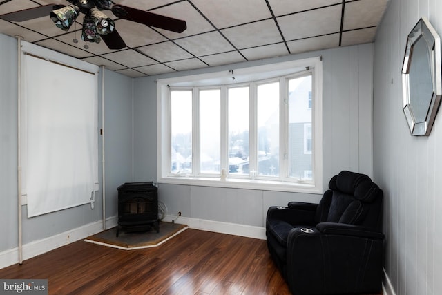 living area with ceiling fan, dark hardwood / wood-style flooring, and a wood stove