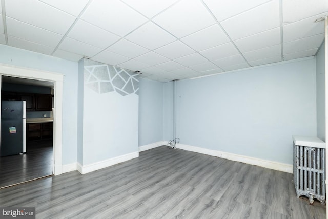 spare room with a paneled ceiling and hardwood / wood-style flooring