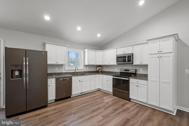 kitchen featuring sink, light hardwood / wood-style flooring, vaulted ceiling, white cabinetry, and stainless steel appliances