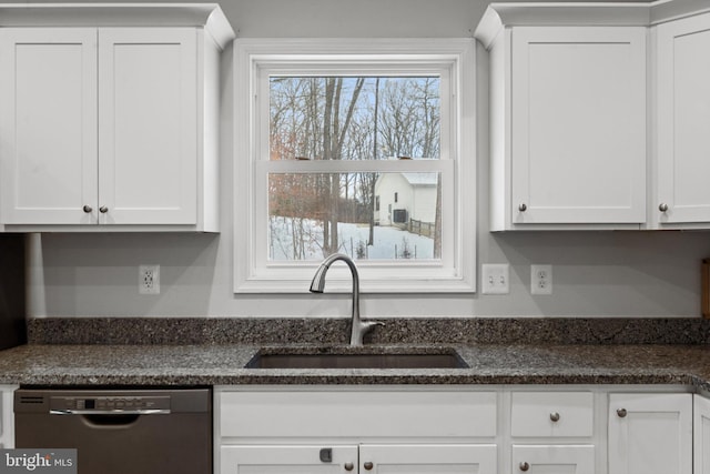 kitchen with stainless steel dishwasher, white cabinetry, sink, and dark stone counters