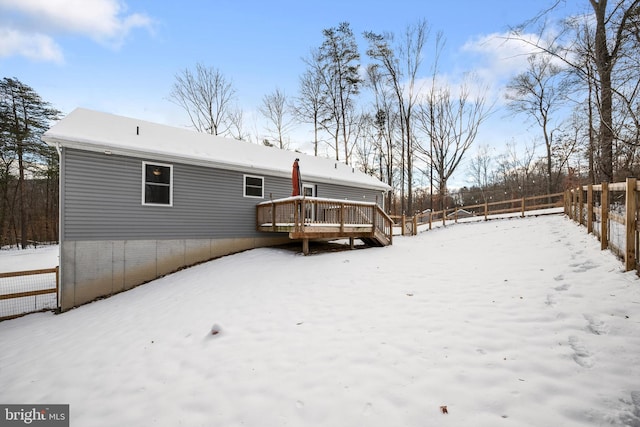 snow covered back of property with a wooden deck