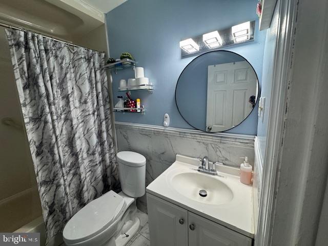 full bathroom with shower / tub combo with curtain, vanity, tile walls, and toilet