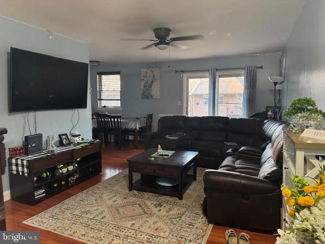 living room featuring ceiling fan and dark wood-type flooring