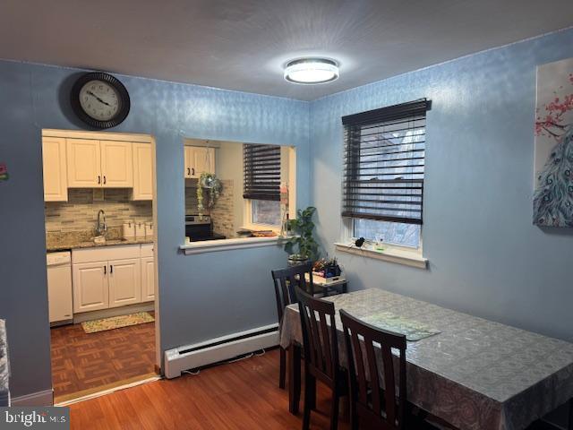 dining room with dark parquet floors, sink, and a baseboard heating unit