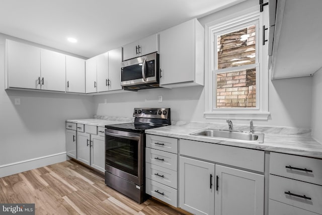 kitchen featuring sink, white cabinets, light hardwood / wood-style flooring, and appliances with stainless steel finishes