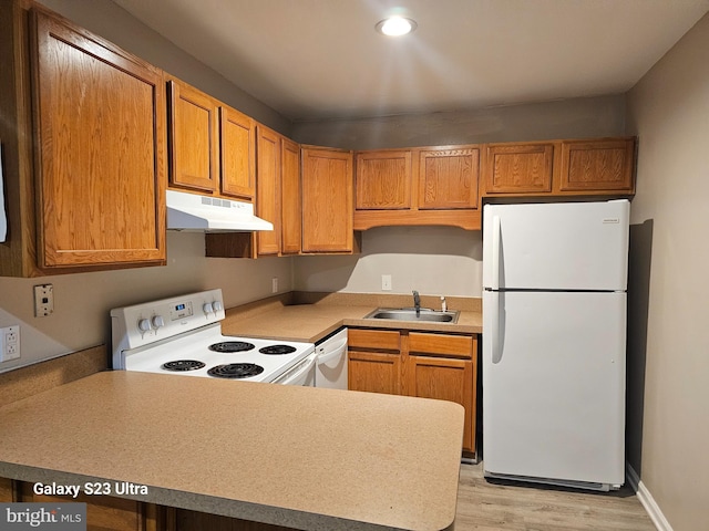 kitchen featuring kitchen peninsula, sink, white appliances, and light hardwood / wood-style flooring