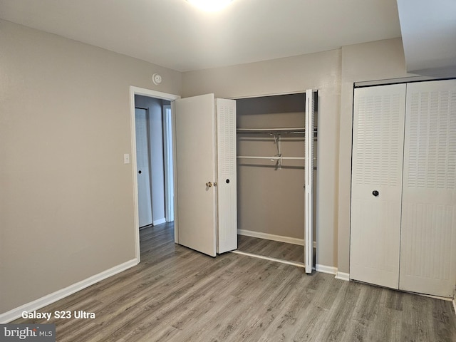 unfurnished bedroom featuring multiple closets and light wood-type flooring