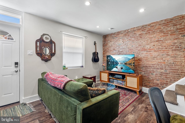 living room featuring dark hardwood / wood-style flooring, brick wall, and a healthy amount of sunlight