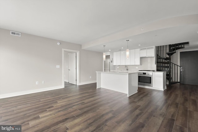 kitchen with a kitchen island, dark wood finished floors, oven, white cabinets, and open floor plan